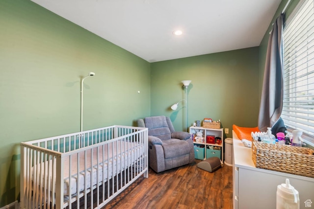 bedroom featuring dark wood finished floors, a crib, and recessed lighting