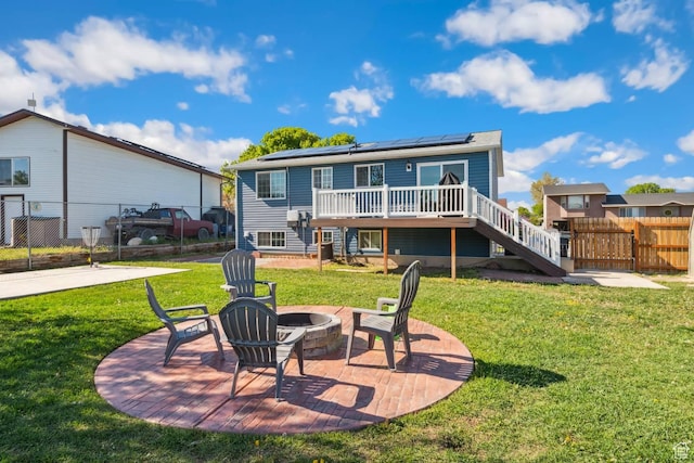 rear view of property featuring stairway, an outdoor fire pit, roof mounted solar panels, a deck, and a patio area