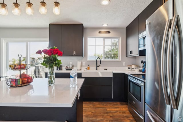 kitchen featuring appliances with stainless steel finishes, a sink, a textured ceiling, dark wood-style floors, and modern cabinets