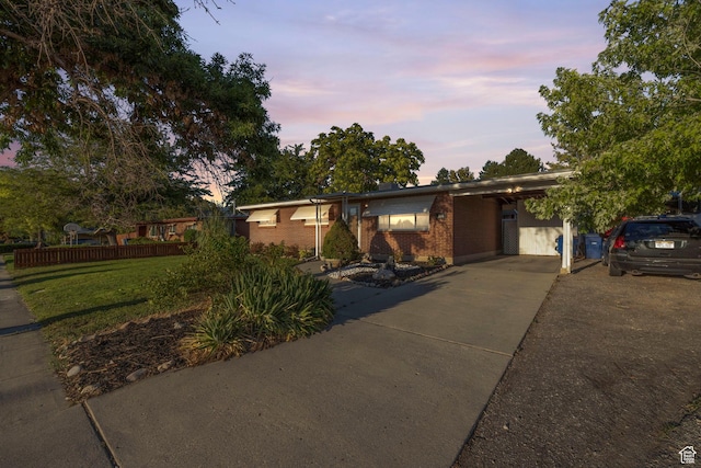 ranch-style house featuring brick siding, driveway, and an attached carport