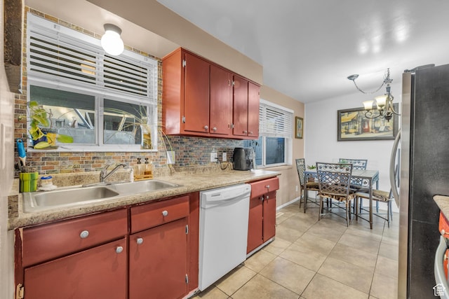 kitchen featuring dishwasher, freestanding refrigerator, a sink, light tile patterned floors, and light countertops