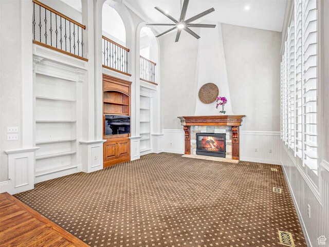 10868 S Prescott Dr E, Sandy, UT 84092 - unfurnished living room with ceiling fan, built in features, carpet, a high ceiling, and a fireplace with flush hearth