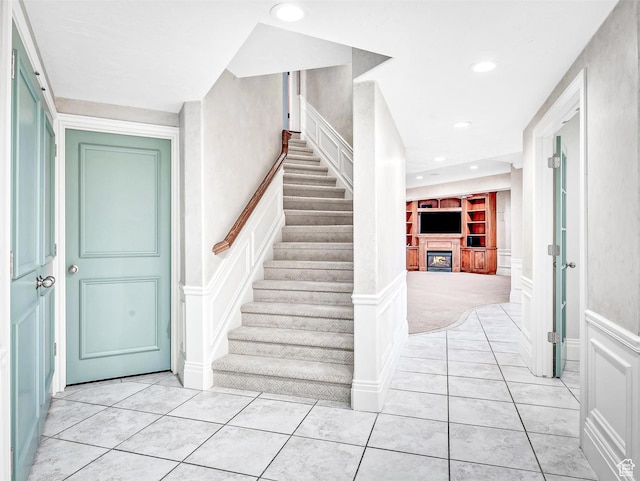 10868 S Prescott Dr E, Sandy, UT 84092 - stairs featuring a decorative wall, a glass covered fireplace, tile patterned floors, built in features, and a wainscoted wall