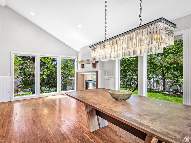 10868 S Prescott Dr E, Sandy, UT 84092 - dining room featuring a premium fireplace, wood finished floors, high vaulted ceiling, recessed lighting, and a wainscoted wall