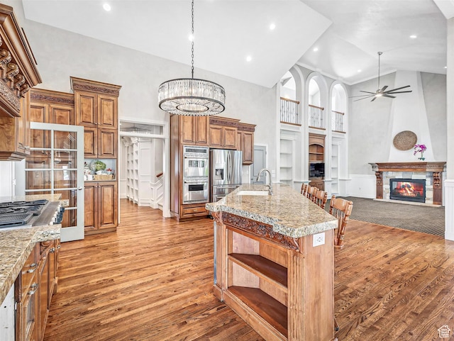 10868 S Prescott Dr E, Sandy, UT 84092 - kitchen featuring a glass covered fireplace, a high ceiling, a sink, stainless steel appliances, and brown cabinets