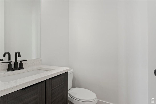 bathroom featuring toilet, vanity, and baseboards