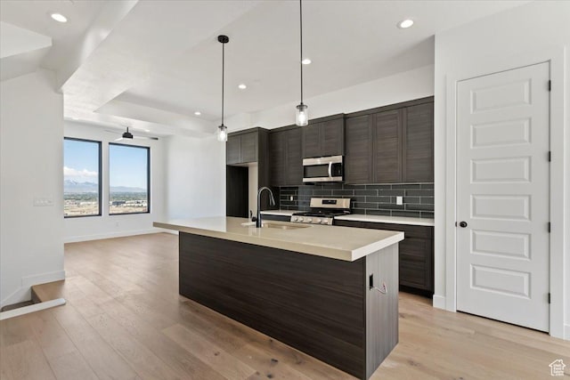 kitchen with stainless steel appliances, a sink, tasteful backsplash, light countertops, and baseboards
