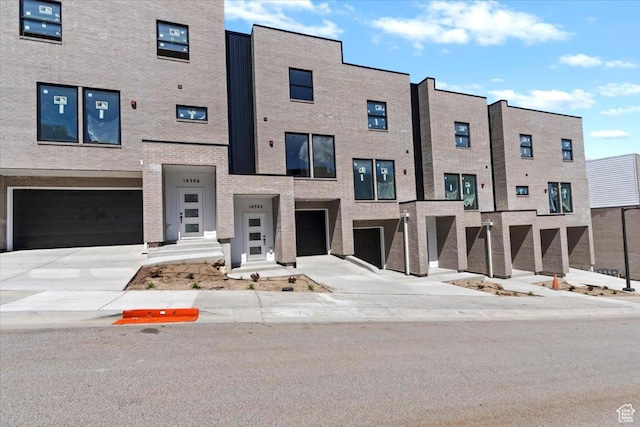 view of front of property with an attached garage, driveway, and brick siding
