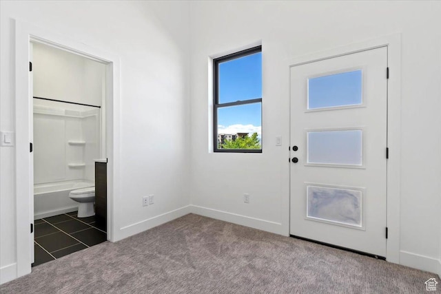 carpeted foyer entrance with baseboards and tile patterned floors