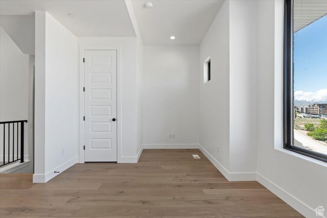 empty room with baseboards, wood finished floors, and recessed lighting