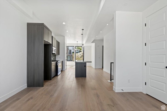 kitchen with appliances with stainless steel finishes, baseboards, light wood-type flooring, a sink, and recessed lighting