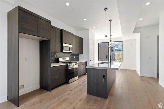 kitchen featuring stainless steel appliances, a sink, baseboards, an island with sink, and recessed lighting