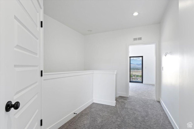 hallway with an upstairs landing, carpet, and baseboards