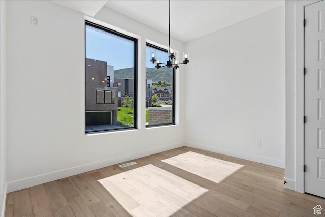 unfurnished dining area featuring a chandelier, baseboards, and wood finished floors