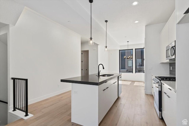 kitchen with gas range oven, a sink, stainless steel microwave, modern cabinets, and white cabinetry