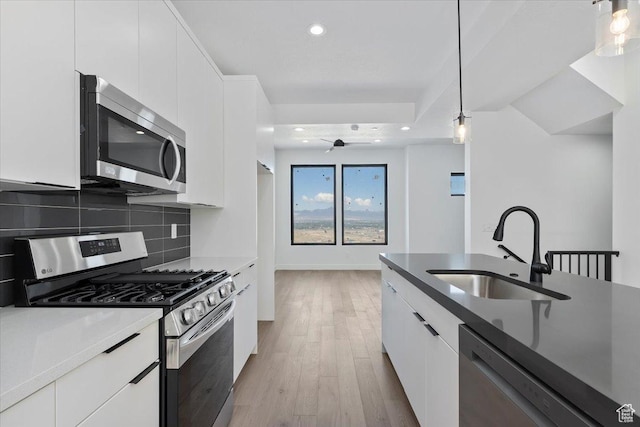 kitchen featuring appliances with stainless steel finishes, a sink, modern cabinets, white cabinets, and recessed lighting