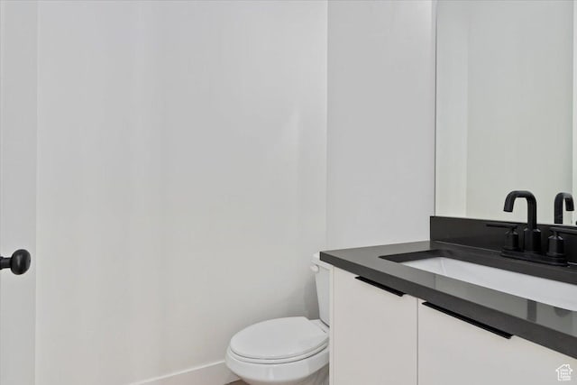 half bath featuring toilet, vanity, and baseboards