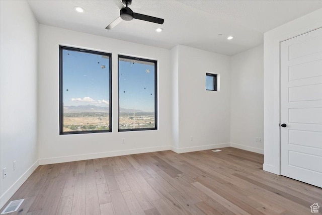 unfurnished room with healthy amount of natural light, wood finished floors, a ceiling fan, baseboards, and recessed lighting