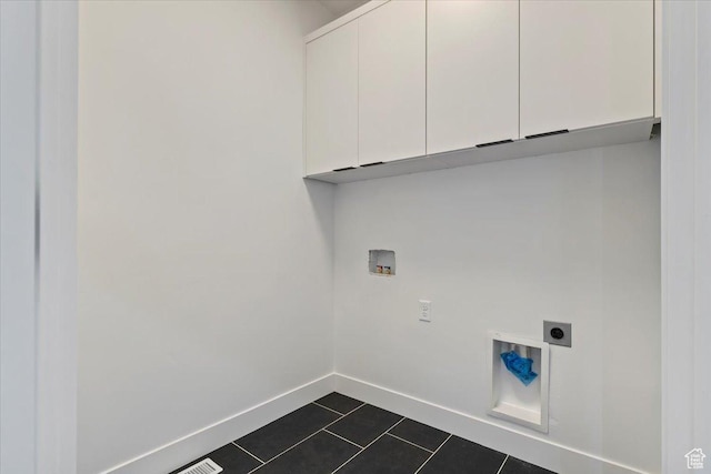 laundry room featuring cabinet space, electric dryer hookup, washer hookup, dark tile patterned flooring, and baseboards