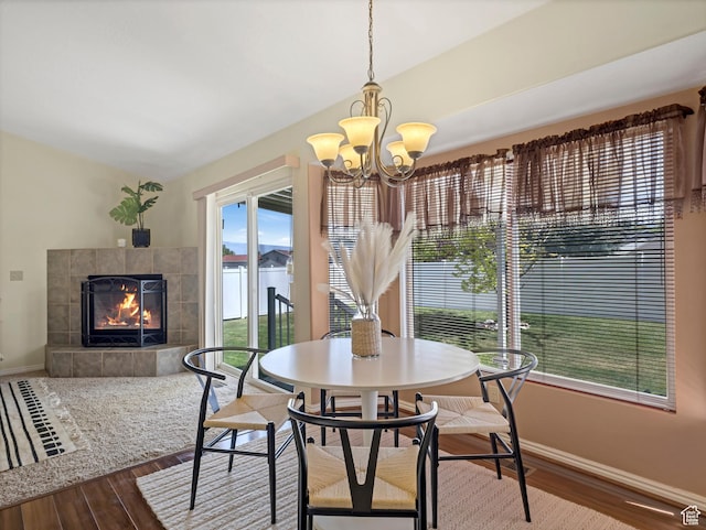 dining area with wood finished floors, baseboards, healthy amount of natural light, and a tile fireplace
