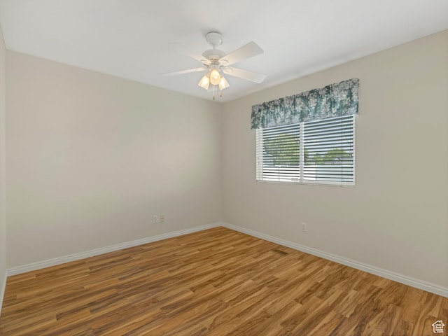 spare room featuring wood finished floors, baseboards, and a ceiling fan