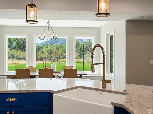 4591 N Abbey Way, Eden, UT 84310 - kitchen featuring a sink, blue cabinetry, light stone counters, pendant lighting, and a chandelier
