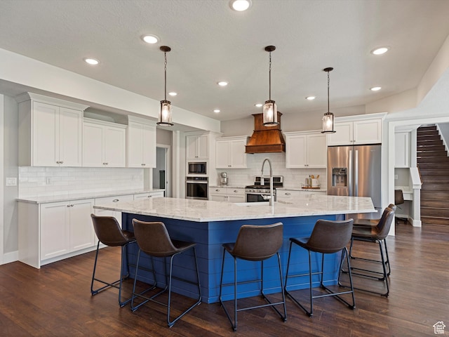 4591 N Abbey Way, Eden, UT 84310 - kitchen with appliances with stainless steel finishes, custom exhaust hood, a spacious island, white cabinetry, and tasteful backsplash