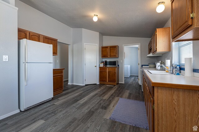 1074 Altus Ln, Fredonia, AZ 86022 - kitchen with freestanding refrigerator, stainless steel microwave, lofted ceiling, brown cabinetry, and dark wood-type flooring