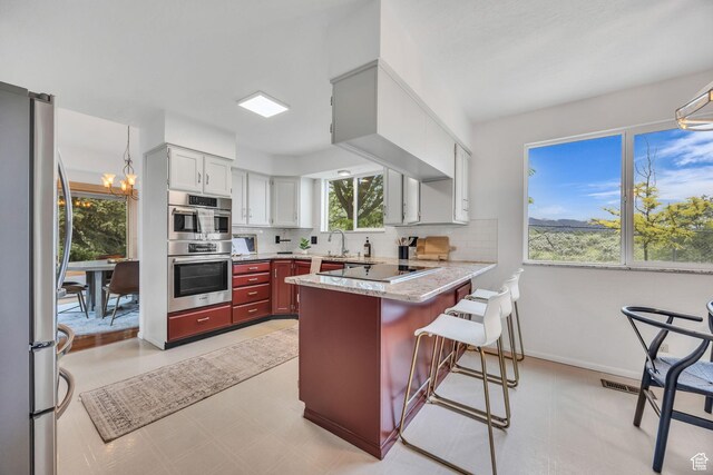 3270 E Danish Hills Cir, Salt Lake City, UT 84121 - kitchen featuring stainless steel appliances, a peninsula, tasteful backsplash, and plenty of natural light