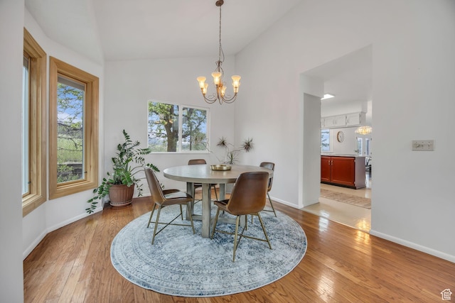 3270 E Danish Hills Cir, Salt Lake City, UT 84121 - dining room featuring vaulted ceiling, a chandelier, light wood-style floors, and baseboards