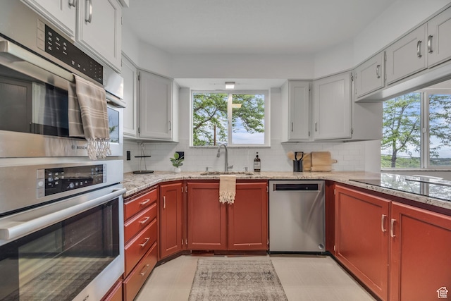 3270 E Danish Hills Cir, Salt Lake City, UT 84121 - kitchen with stainless steel appliances, a sink, decorative backsplash, light stone countertops, and light floors