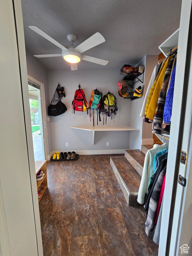 mudroom with ceiling fan, a textured ceiling, baseboards, and stone finish floors