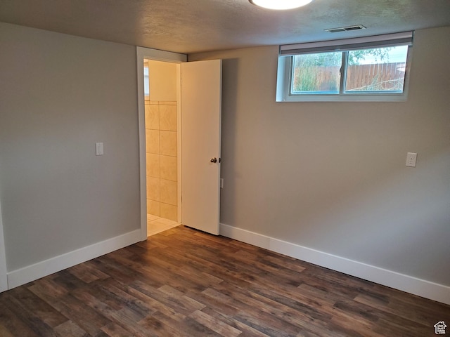 spare room with baseboards, dark wood-type flooring, and a textured ceiling