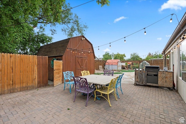 view of patio / terrace with outdoor dining area, an outbuilding, a fenced backyard, and a storage shed