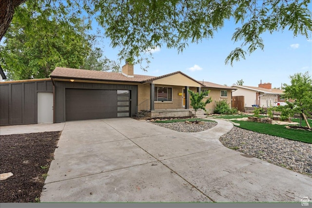single story home featuring covered porch, a chimney, an attached garage, and concrete driveway