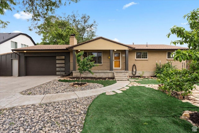 single story home featuring a garage, concrete driveway, a chimney, brick siding, and a front lawn