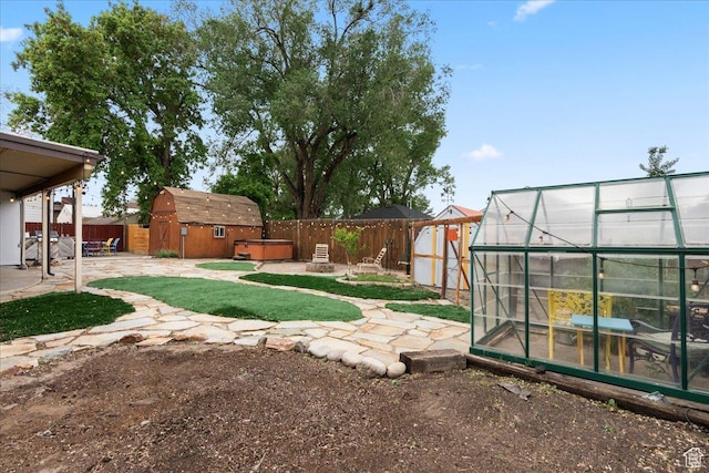 fenced backyard featuring an outbuilding, an exterior structure, a patio, and a hot tub