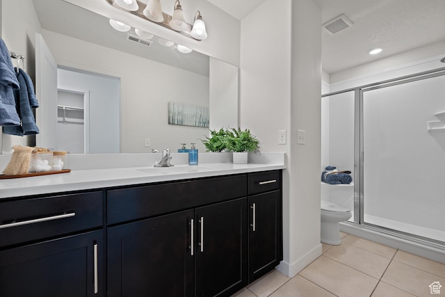 bathroom with tile patterned flooring, a stall shower, toilet, and vanity