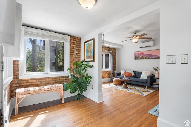 86 N B St Unit 34, Salt Lake City, UT 84150 - living room with a wall mounted AC, light wood-style flooring, ceiling fan, brick wall, and a textured ceiling