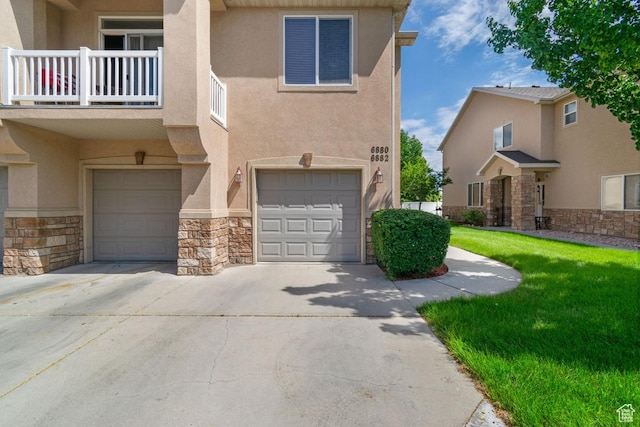 townhome / multi-family property featuring stone siding, stucco siding, a garage, driveway, and a balcony
