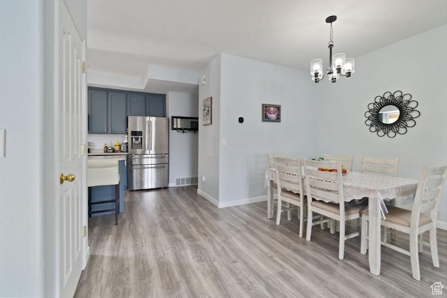 dining space featuring wood finished floors, a chandelier, and baseboards