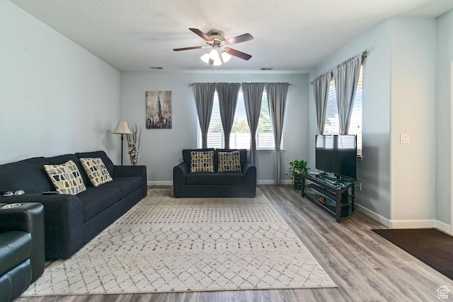 living room featuring a ceiling fan, wood finished floors, and baseboards