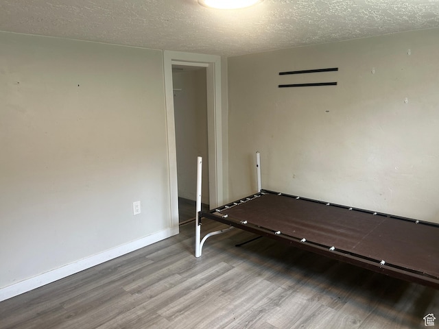 spare room featuring wood finished floors, a textured ceiling, and baseboards