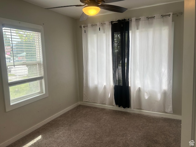carpeted spare room featuring plenty of natural light, ceiling fan, and baseboards