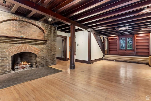 34 S Haxton Pl, Salt Lake City, UT 84102 - unfurnished living room with hardwood / wood-style floors, beamed ceiling, stairway, baseboards, and a brick fireplace
