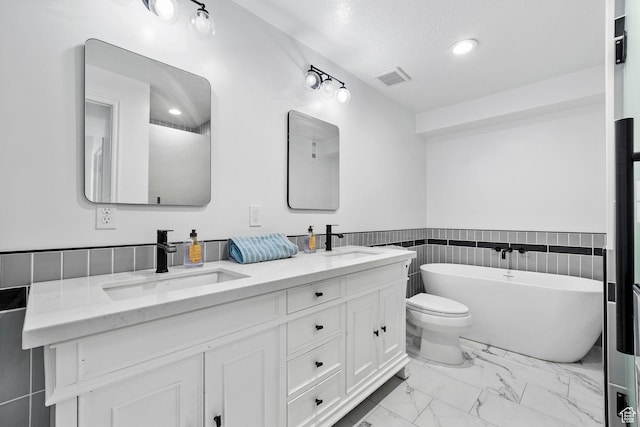 13956 S Wild Colt Cir, Herriman, UT 84096 - bathroom featuring marble finish floors, a soaking tub, double vanity, wainscoting, and toilet