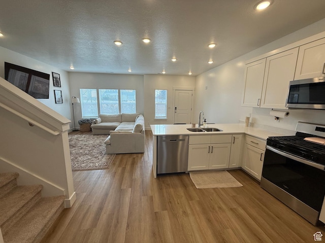 81 W 925 N, Brigham City, UT 84302 - kitchen featuring appliances with stainless steel finishes, a sink, a peninsula, white cabinetry, and light wood-style floors
