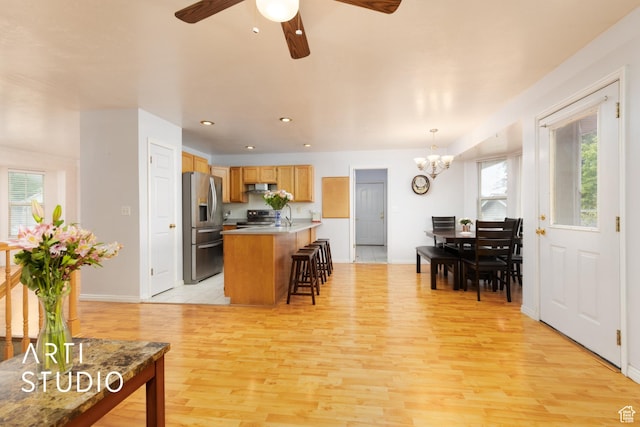 2956 W Mackay Meadows Pl, West Valley City, UT 84119 - kitchen featuring appliances with stainless steel finishes, a breakfast bar, light wood finished floors, a ceiling fan, and a chandelier