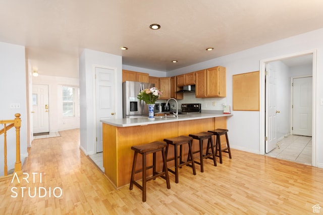 2956 W Mackay Meadows Pl, West Valley City, UT 84119 - kitchen featuring appliances with stainless steel finishes, under cabinet range hood, a peninsula, light wood-style flooring, and backsplash