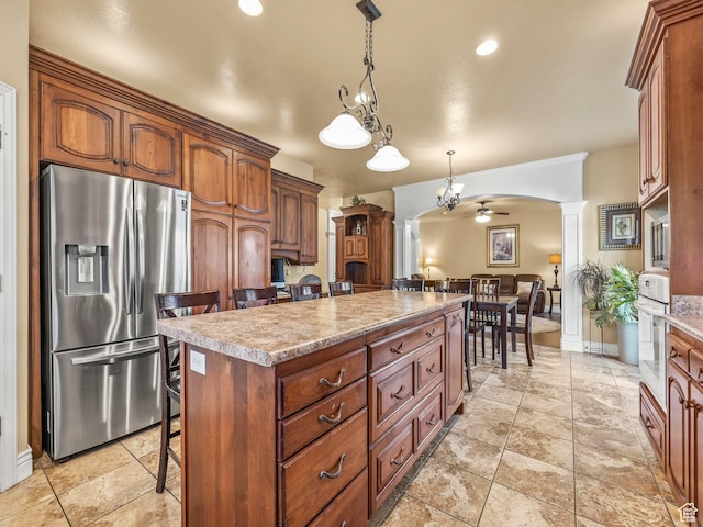 kitchen featuring stainless steel fridge, a kitchen island, ornate columns, a breakfast bar area, and oven